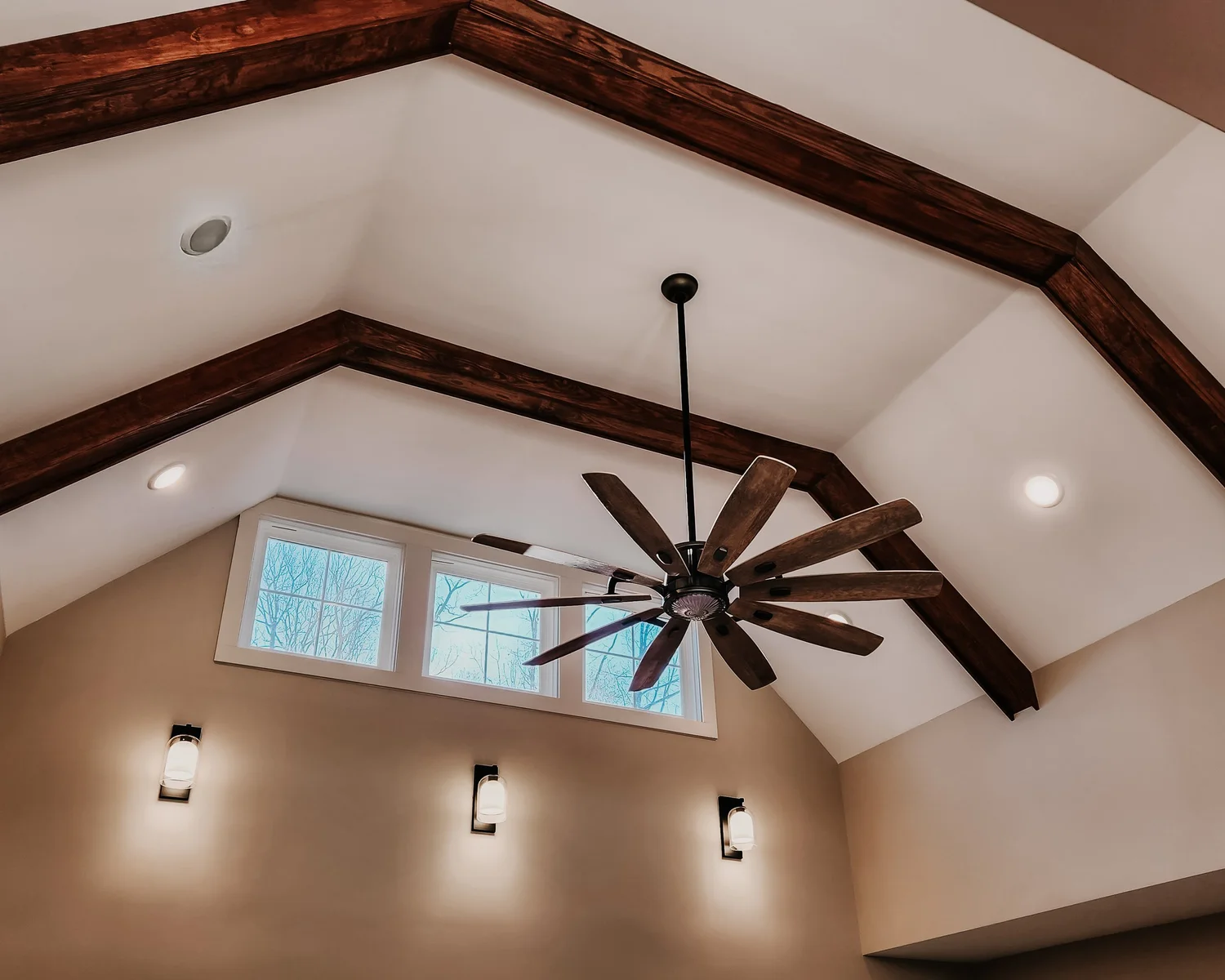 Vaulted ceiling with wooden beams and fan in a custom home build, highlighting our fully turnkey services.