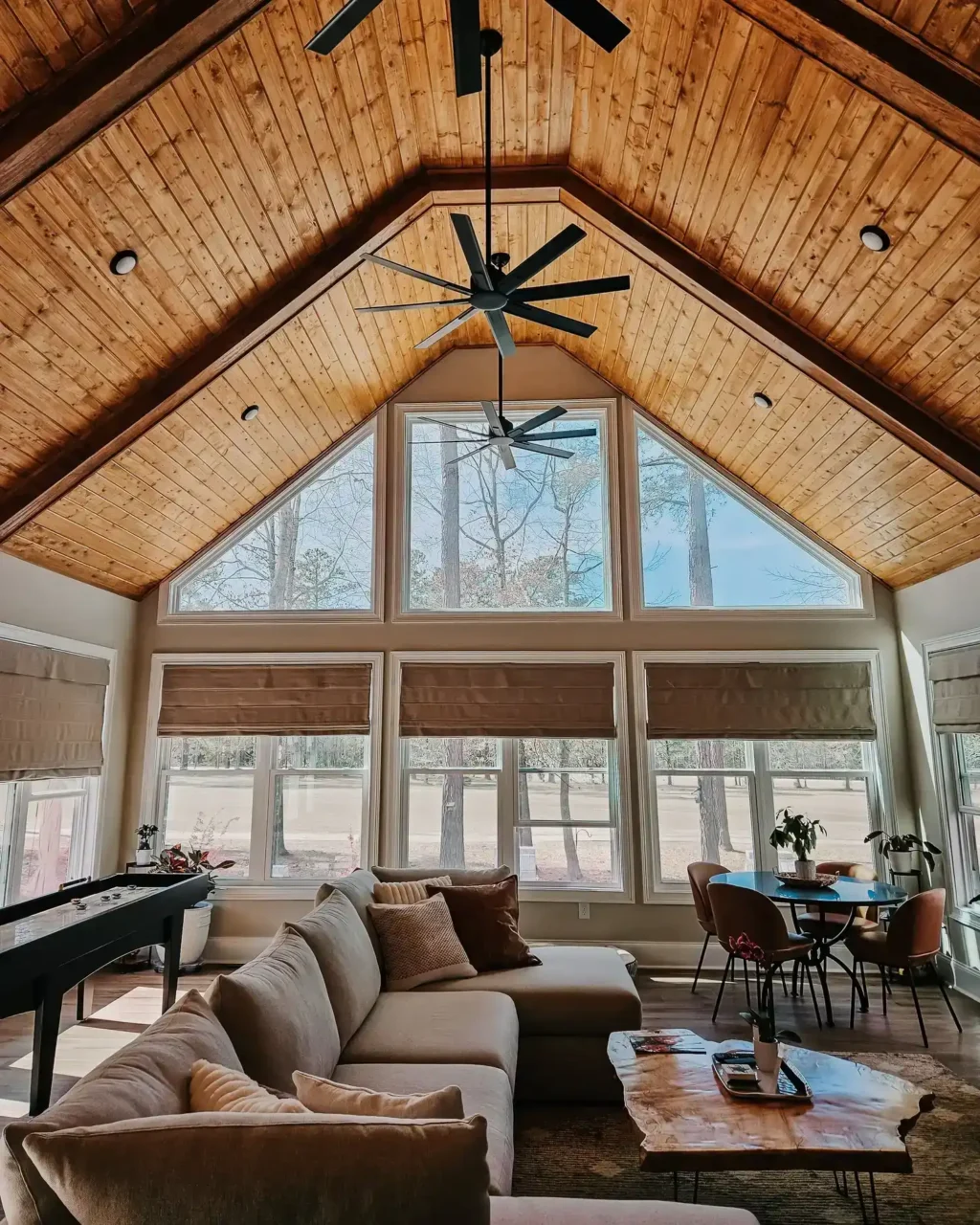 Spacious living room with vaulted wooden ceiling, large windows, and cozy seating in a Lake Greenwood home.