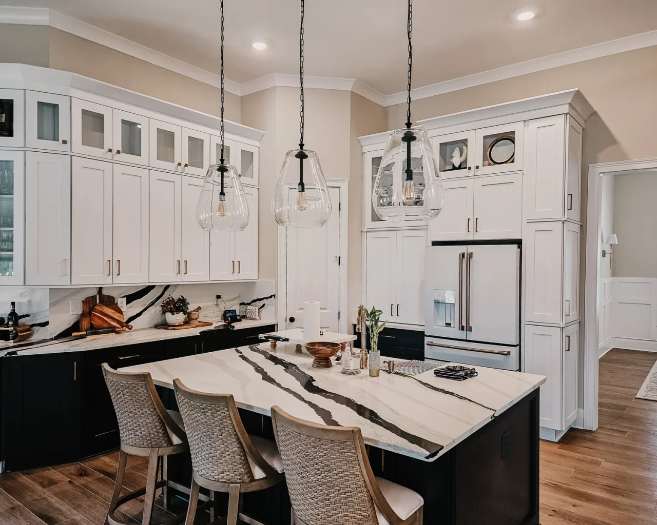 Modern kitchen in Lake Greenwood home with marble island, white cabinets, pendant lights, and wood flooring.