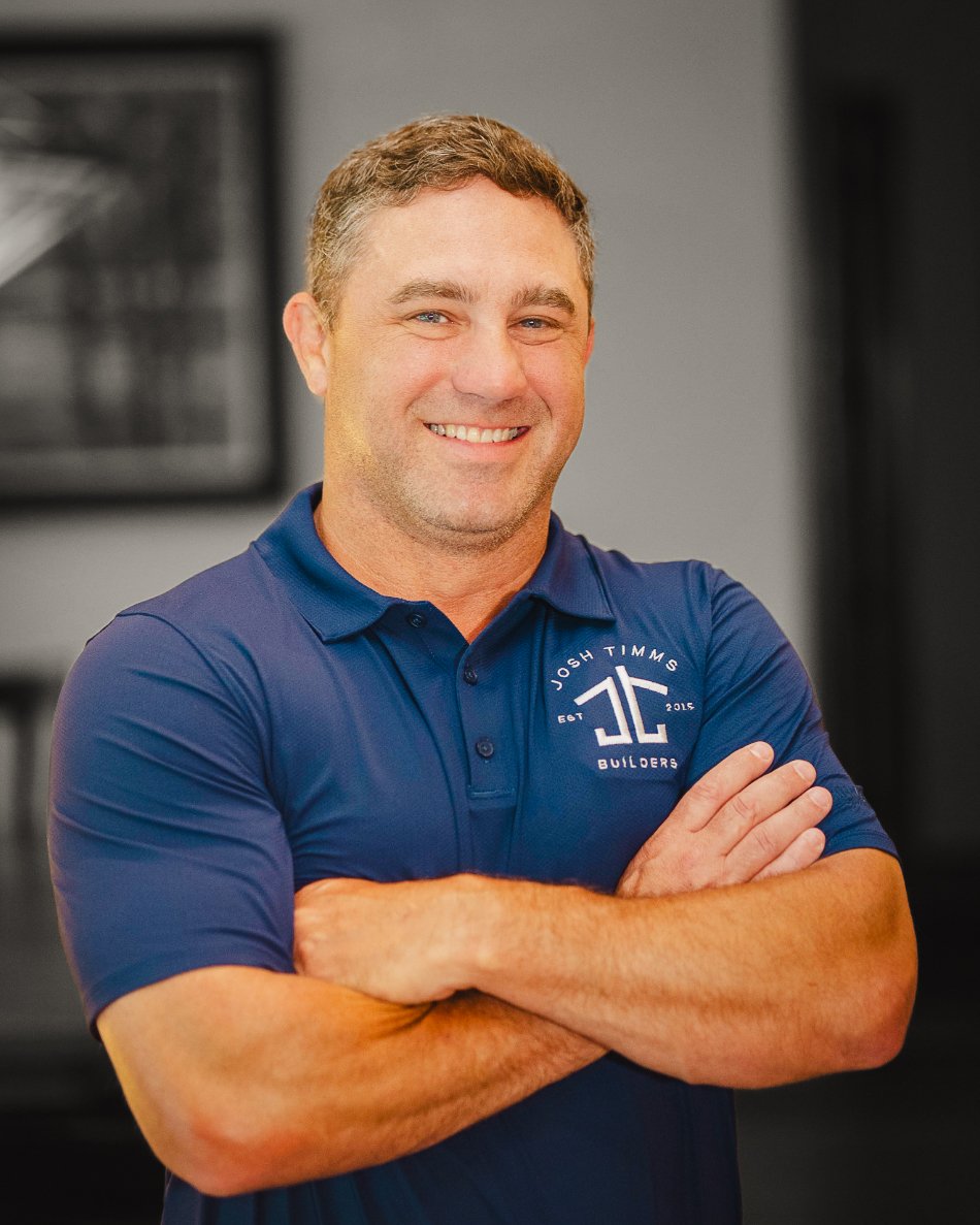 Smiling man in a blue Josh Timms Builders shirt, embodying the higher standard in custom homebuilding.