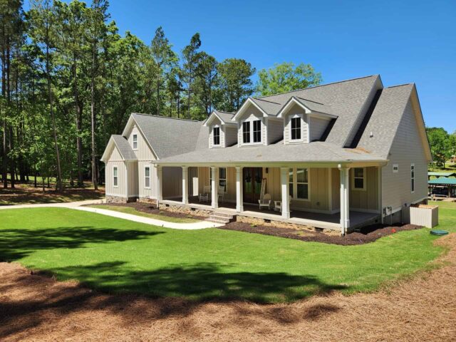 Custom home with a large porch surrounded by lush trees on your land in Upstate SC, ready for your dream home.